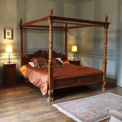 Antique bed with Jamestown mattress, green walls, maroon sheets, oriental rug—classic elegance.