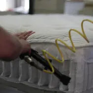 Quilted mattress panel being attached to pocket coil, showcasing craftsmanship.