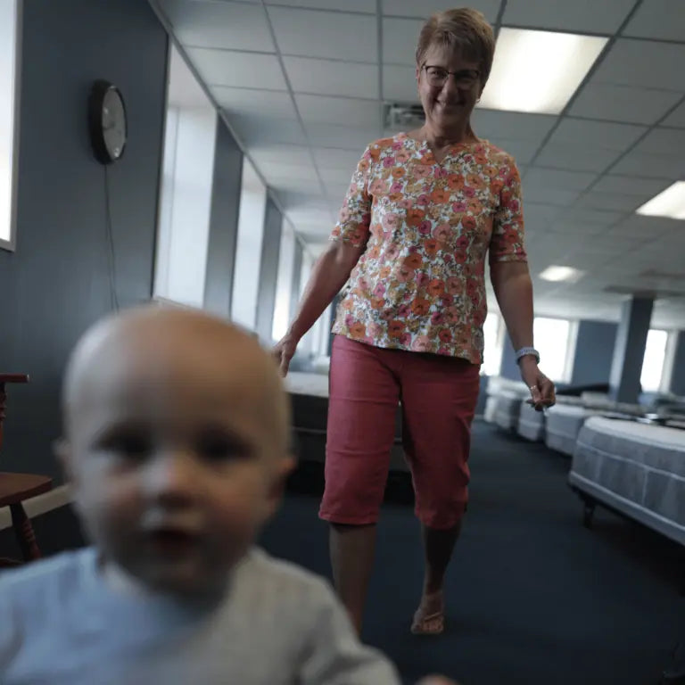 Toddler, future Jamestown Mattress maker, exploring the showroom with his grandmother, a current employee, following closely behind.