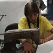 Woman sewing mattress cover in Jamestown factory, highlighting handmade work.